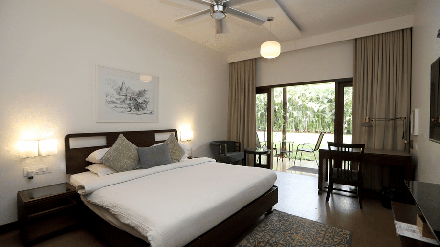 A wide-angle shot of the Studio highlighting the desk area, ceiling fan, and elegant neutral-toned curtains | Trance Sunderban Resort