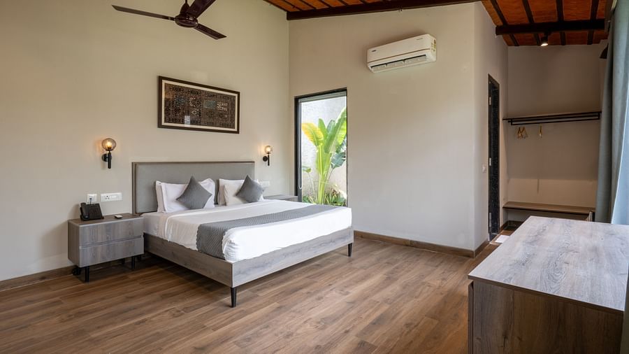  Ananta Garden Villa bedroom at Trance Veechika Resort: a spacious room with a bed, large window, fan, and wooden floor.