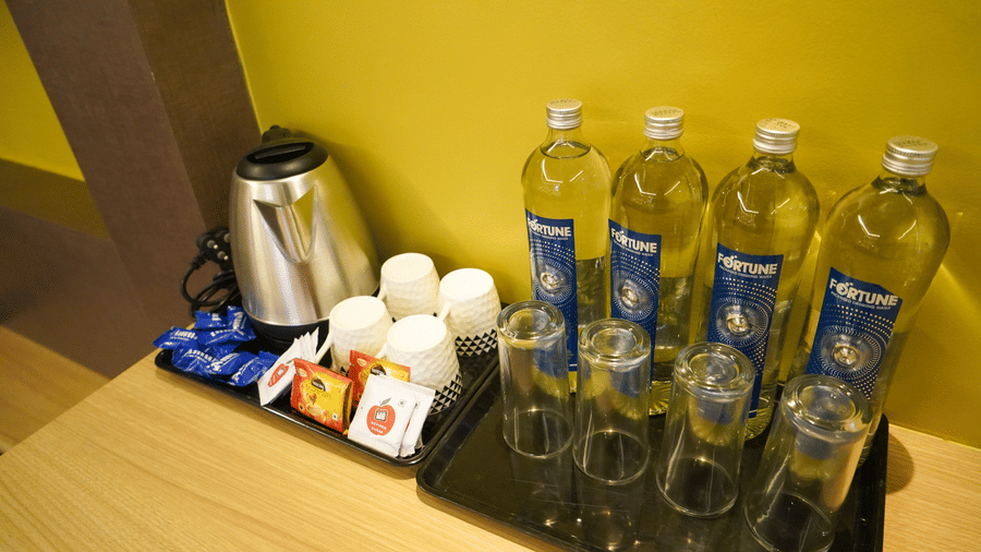 Close-up of a hospitality tray with an electric kettle, bottled water, mugs, and tea-making facilities at Trident The Boutique Hotel, Ooty.