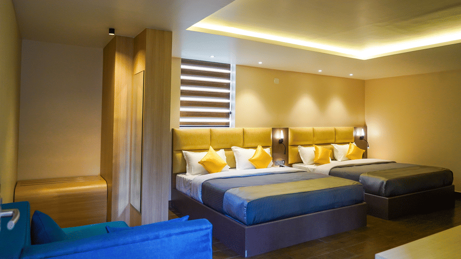 Spacious hotel room with two double beds, yellow accents, and contemporary wooden partitions at Trident The Boutique Hotel, Ooty.