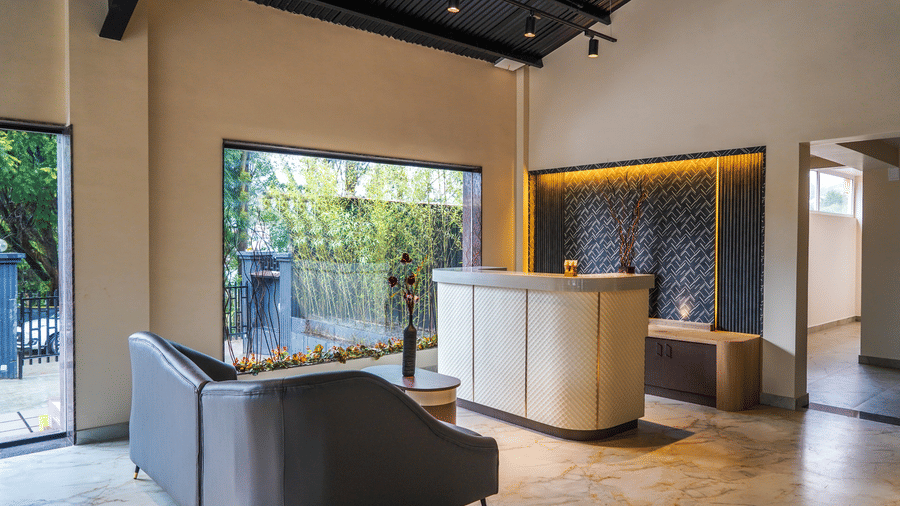 Bright reception area with large windows, minimalist grey sofas, and elegant interior design with soft lighting at Trident The Boutique Hotel, Ooty.