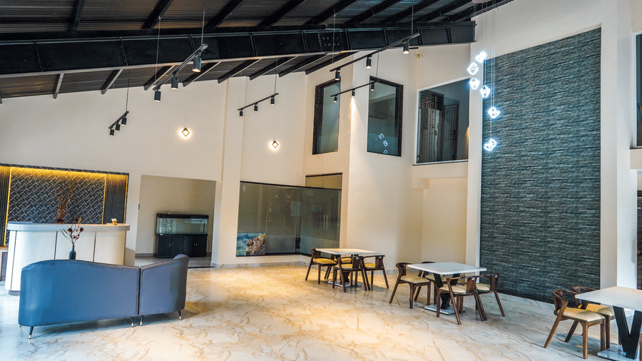 Modern hotel lobby featuring high ceilings, contemporary light fixtures, and a sleek reception desk with seating areas at Trident The Boutique Hotel, Ooty.