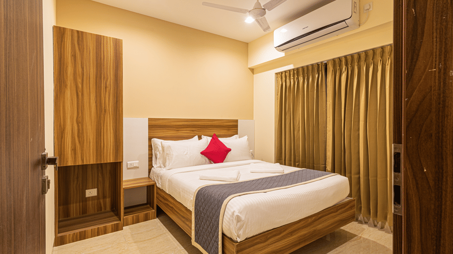 A cosy hotel room with warm lighting, a large bed, and wooden furniture - Urban Comforts