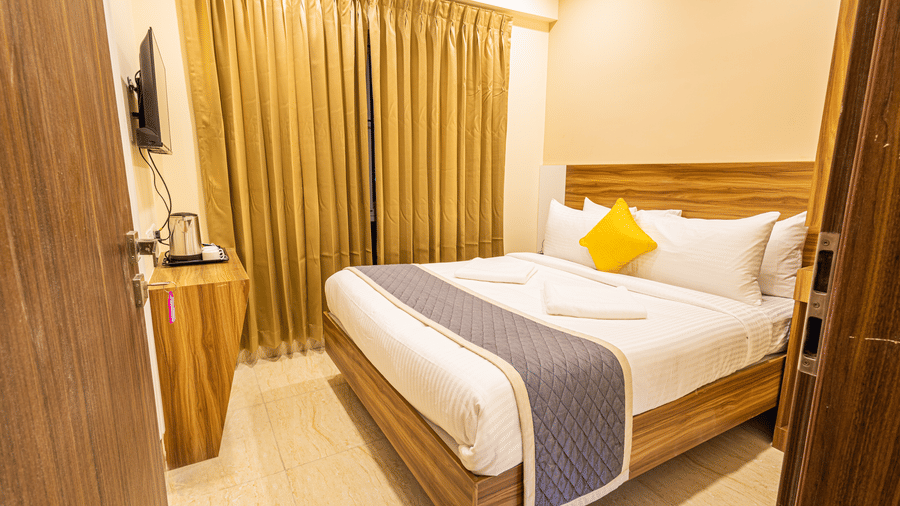 A wide-angle view of a well-appointed hotel room with a desk and wardrobe - Urban Comforts