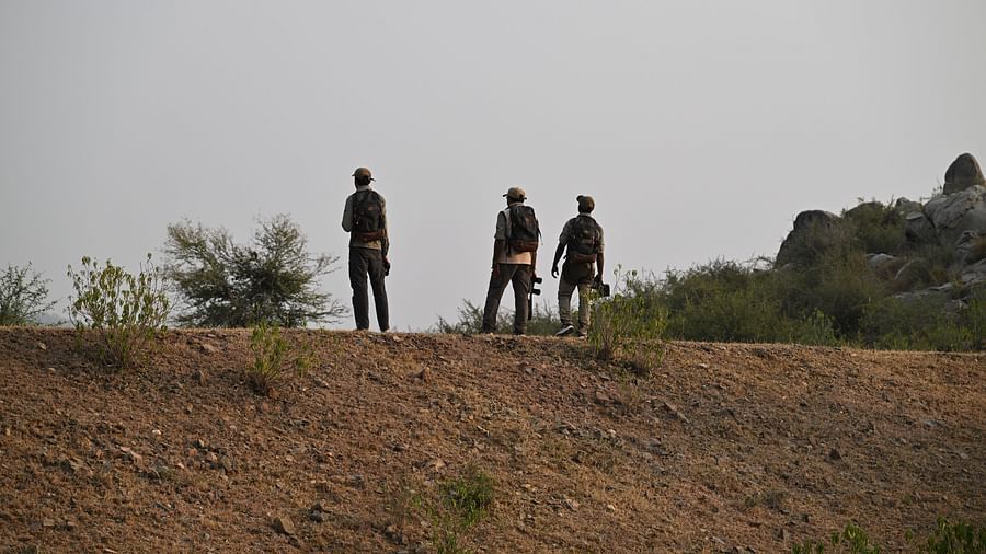 An image of three men standing on the rocky mountains - An image of a jeep parked amidst the rocky mountains - Utsav Camp Sariska