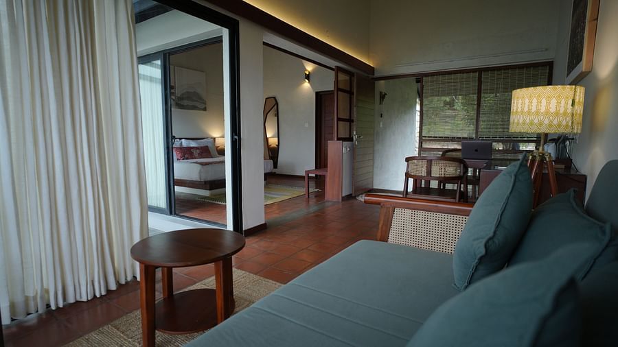  A spacious living area at Vaasta Vagamon with a sofa, a coffee table, and an open doorway leading to a bedroom.