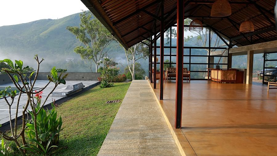  A spacious open-air pavilion at Vaastha Vagamon, featuring an exposed roof structure and offering panoramic views of the surrounding hills.