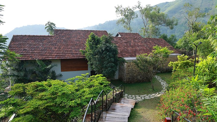  A building with a tiled roof at Vaastha Vagamon, nestled amidst lush greenery and offering expansive valley views.