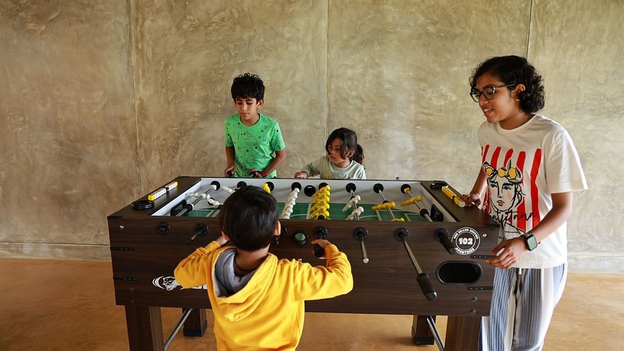 Four children playing foosball at Vaasta Vagamon, actively engaged in a lively game.