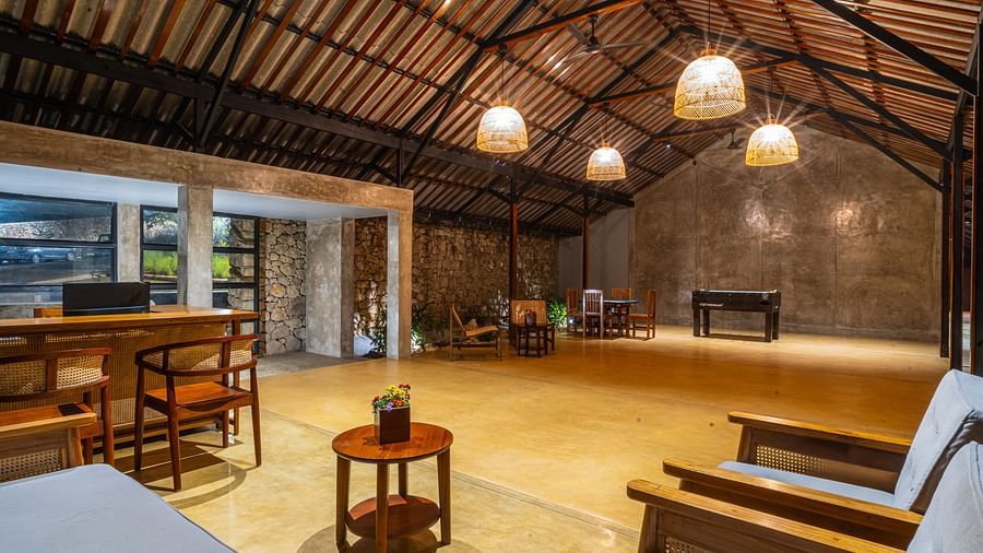  A common area at Vaastha Vagamon with exposed beams, pendant lighting, seating, and a bar counter.