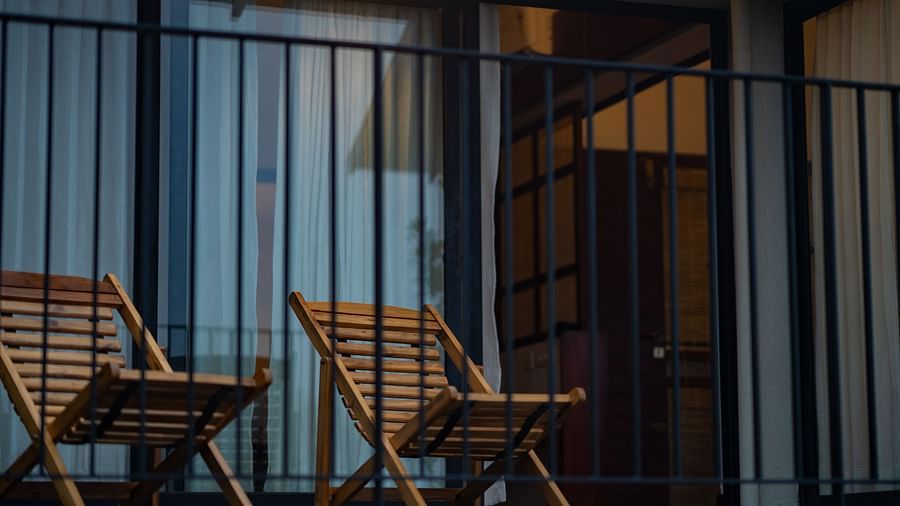  A private balcony at Vaasta Vagamon with two wooden lounge chairs, enclosed by a railing, offering a cozy outdoor seating area.