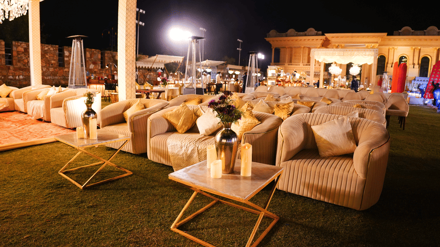 An evening outdoor event setup at Valley By Grassfield, with numerous couches, coffee tables, and ambient lighting under a large canopy.