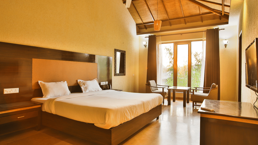 Bedroom with white linens, seating area, and large windows at Valley by Grassfield, a resort in Jaipur.