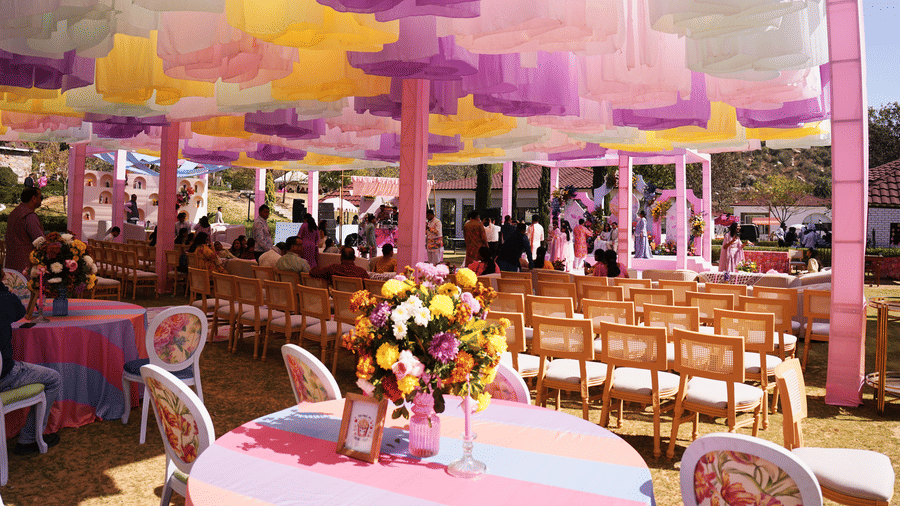 Indoor event hall with floral centrepieces on dining tables at Valley by Grassfield, a wedding venue in Jaipur.