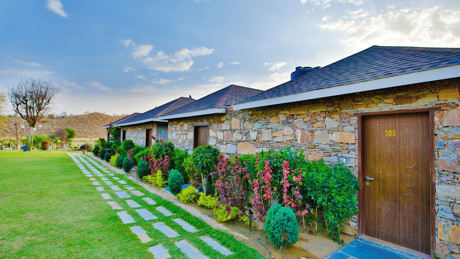 Cottage with rock walls and wooden doors at Valley by Grassfield, a resort in Jaipur.
