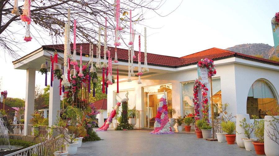 Wedding entrance decor with hanging florals from tree branches at Valley by Grassfield, a wedding venue in Jaipur.