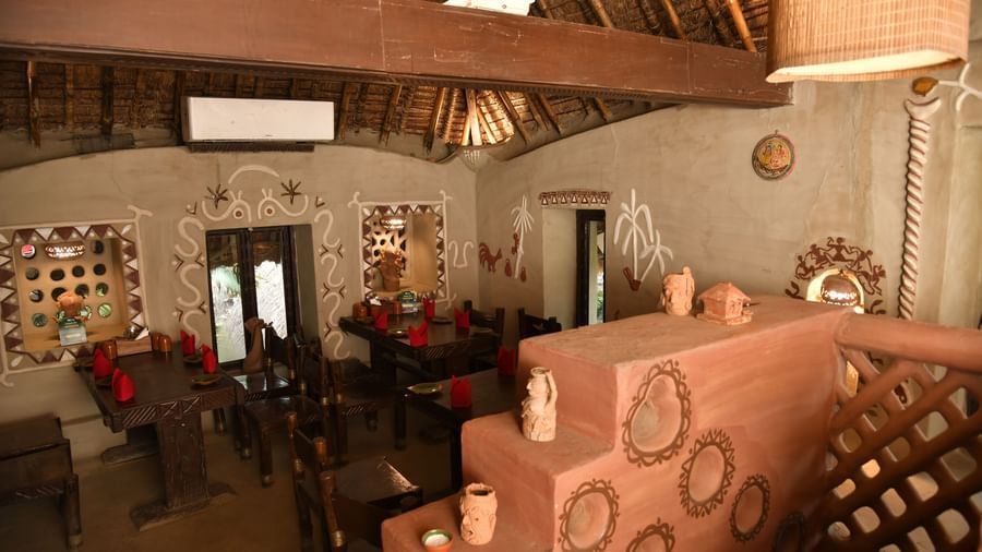 The interior of a restaurant with traditional decor, featuring a unique, textured wall and a clay oven or fireplace | Bhoomi Restaurant