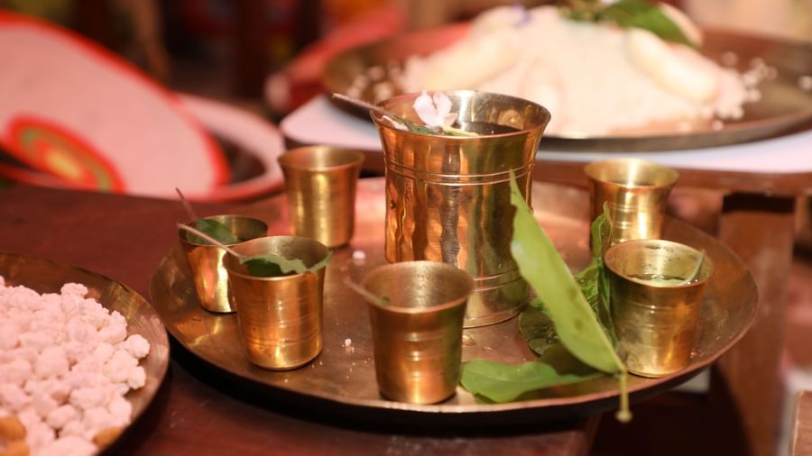 A traditional Indian thali meal with rice, curries, and drinks served in brass utensils | Vedic Village Spa Resort, Kolkata
