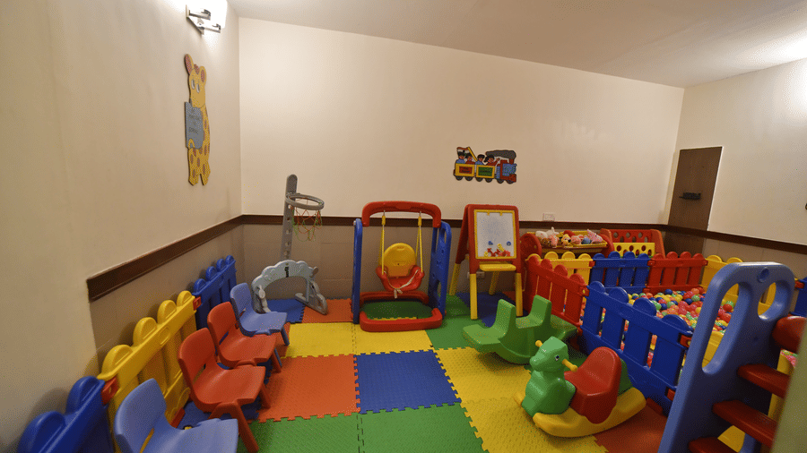A colorful indoor kids play area at Vedic Village Spa Resort featuring plastic slides ride-on toys foam mats and bright wall artwork in a cheerful and safe setting.