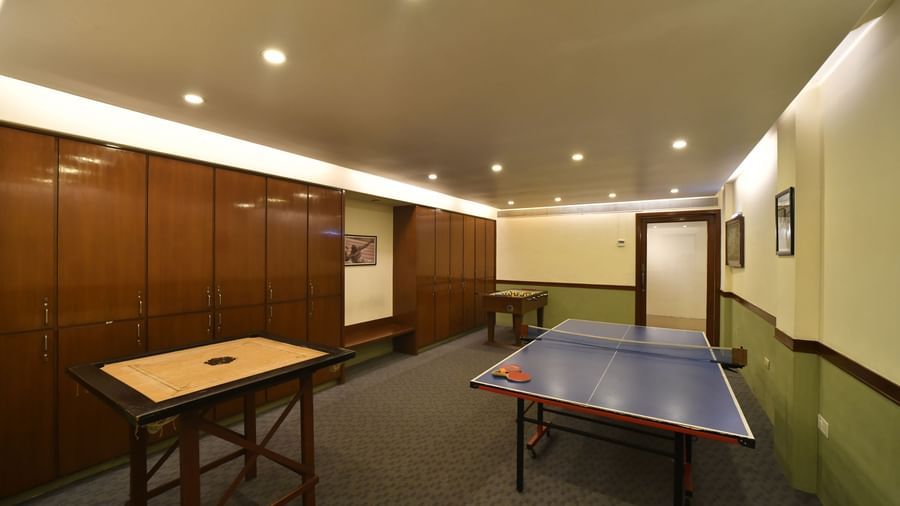 An indoor room with wooden walls featuring a table tennis table and another table