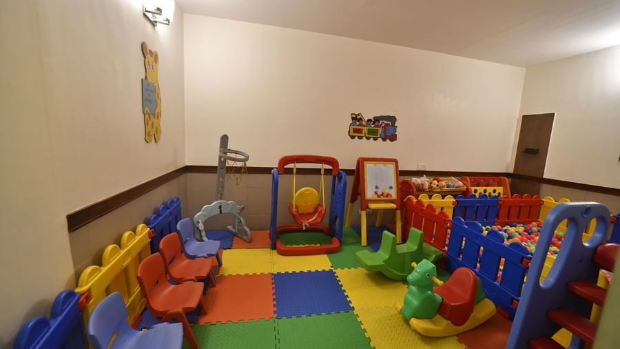 A colourful indoor play area is filled with various plastic toys and soft mats