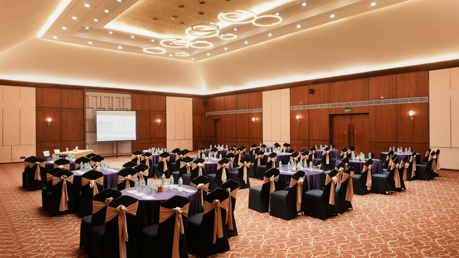 Large banquet venue at Vedic Village Spa Resort featuring round table seating, elegant décor, and a spacious setting for weddings, receptions, and social gatherings.