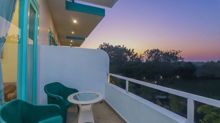 A balcony at Vedikant Resorts The Mallard Corbett features chairs and a table with a view of the landscape.