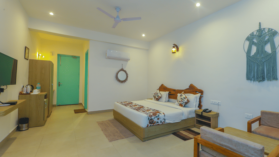 A spacious bedroom at Vedikant Resorts The Mallard Corbett features a bed, seating, and decor in a well-lit setting.