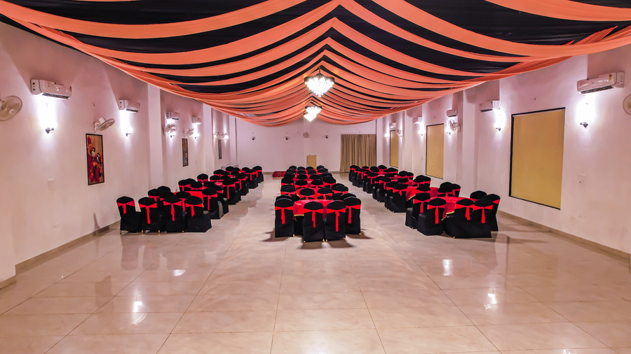 An empty banquet hall at Vedikant Resorts The Mallard Corbett has rows of chairs set up for an event under a decorated ceiling.