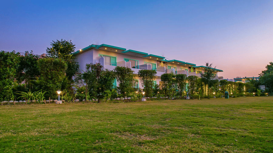 View of Vedikant Resorts The Mallard Corbett at twilight showcases the buildings and open grassy area.