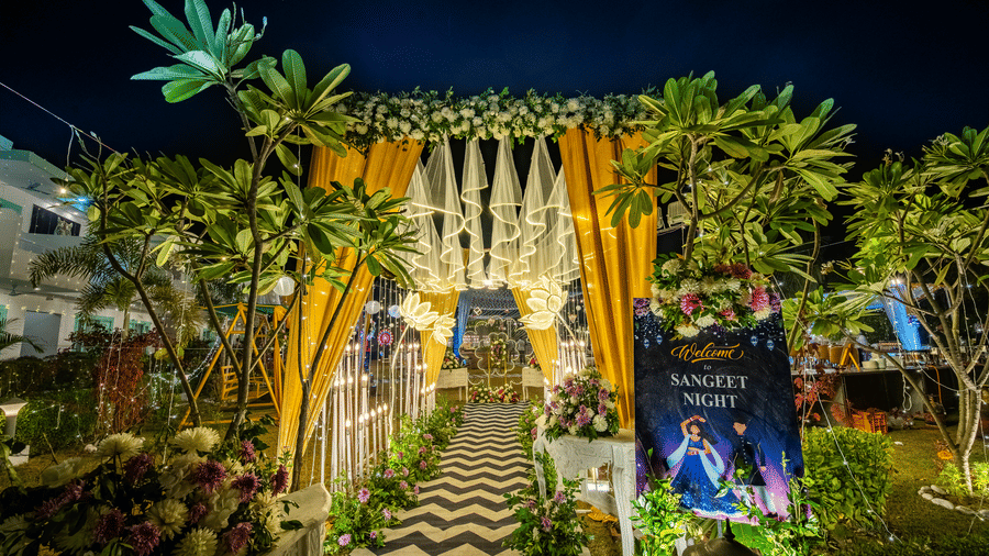 A grand, brightly lit floral and green entrance archway at an evening wedding function at Vedikant Resorts The Mallard Corbett.