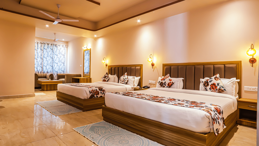 A comfortable bedroom at Vedikant Resorts The Mallard Corbett offers beds, a seating arrangement, and warm lighting.