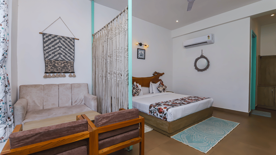 Inside view of a room at Vedikant Resorts The Mallard Corbett with a bed, bench, large window, and a wall art feature.