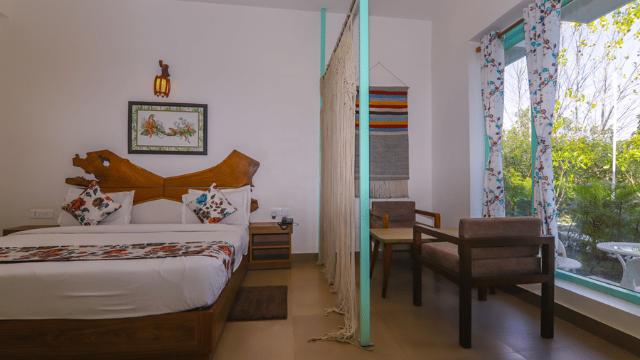 Bright and airy guest room at Vedikant Resorts The Mallard Corbett with a double bed, glass doors, and a sitting area.