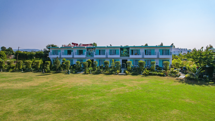Open lawn at Vedikant Resorts The Mallard Corbett with trimmed grass, resort buildings in the background, and no visible guests.