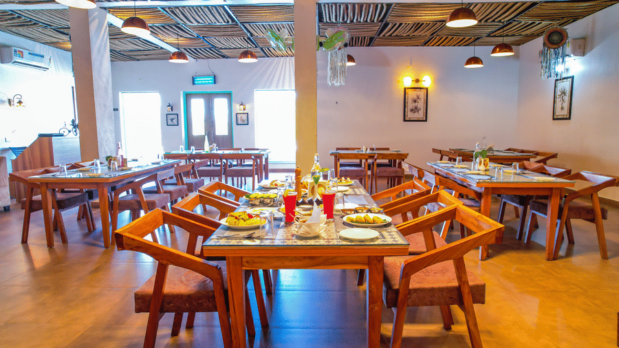 A dining area at Vedikant Resorts The Mallard Corbett displays wooden tables and chairs in a comfortable setting.
