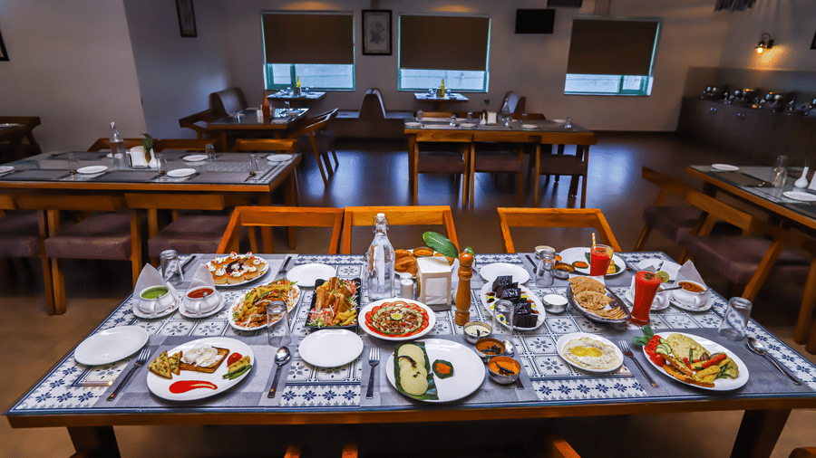 A dining area at Vedikant Resorts The Mallard Corbett features set tables and chairs in a brightly lit space.