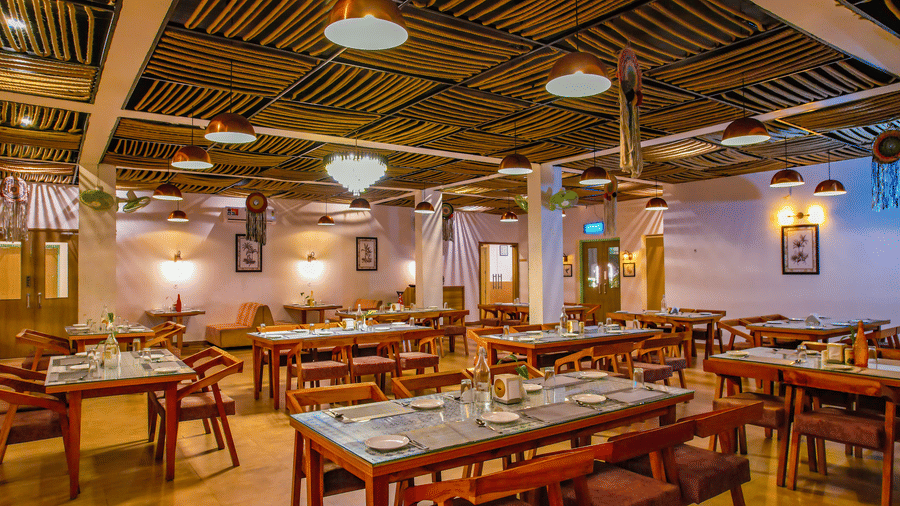 Several set tables and chairs are arranged in a spacious dining hall at Vedikant Resorts The Mallard Corbett.