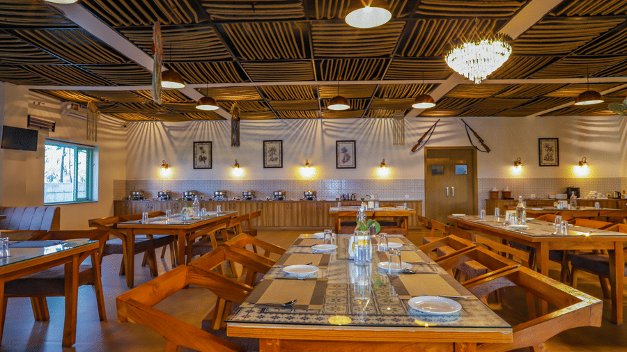 A long table with chairs extends through a well-lit dining area at Vedikant Resorts The Mallard Corbett.