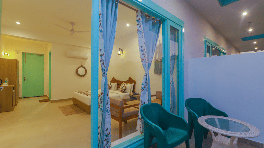 A bright room at Vedikant Resorts The Mallard Corbett opens to a balcony with chairs and a table.