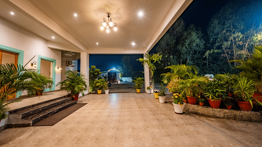 Entrance of the Vedikant Resorts The Mallard Corbett featuring a driveway surrounded by plants and flower pots on either side.