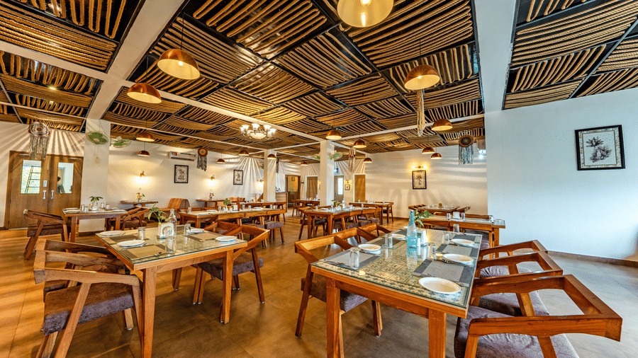 Himalayan Spices at Vedikant Resorts The Mallard Corbett featuring chairs, sofas, tables, fans  and hanging bulbs from the ceilings, and a chandelier at the centre.