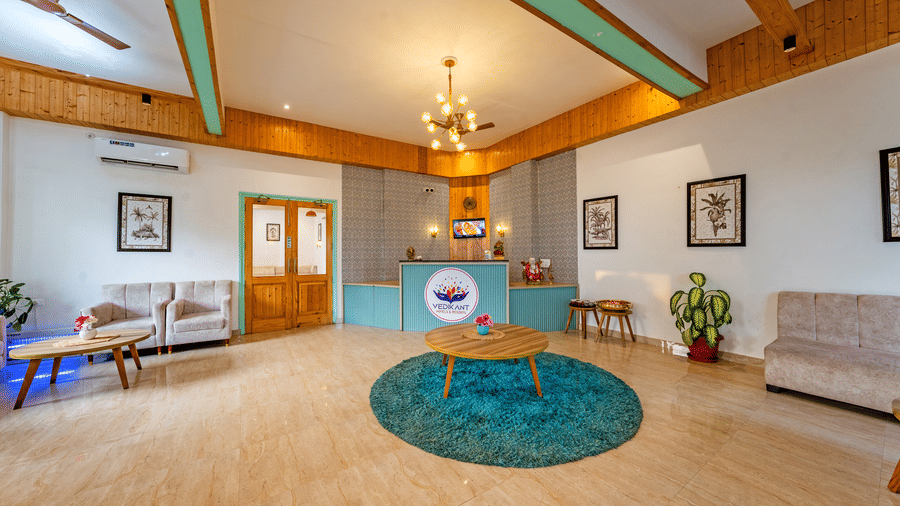 Reception lobby at Vedikant Resorts The Mallard Corbett featuring a reception desk and a seating area featuring sofa sets, centre table with flower vase, and other decorative elements.