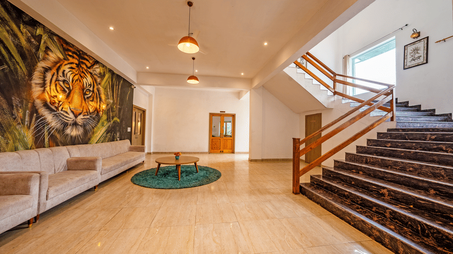 Reception lobby at Vedikant Resorts The Mallard Corbett featuring sofa and a centre table, and a flight of stairs leading to other floor.
