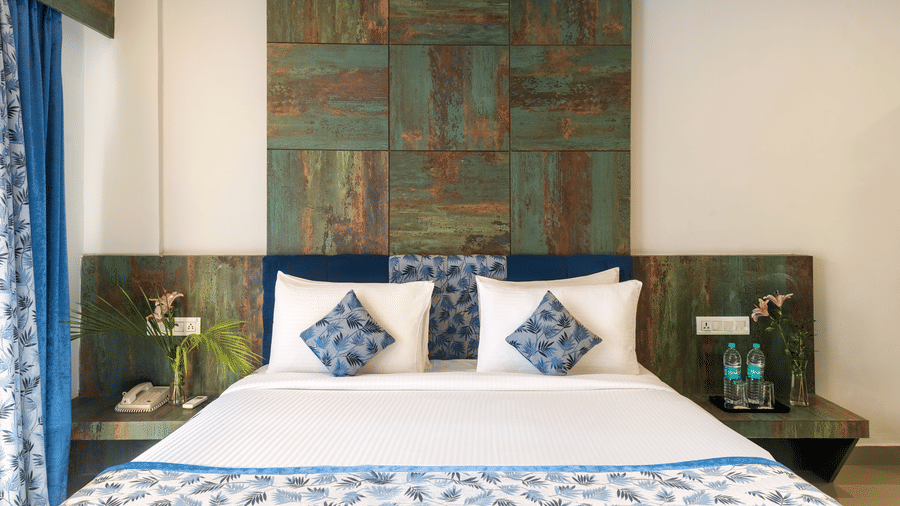 A bedroom with a made bed, decorative pillows, and artwork on the wall - Via Lakhela Resort & Spa