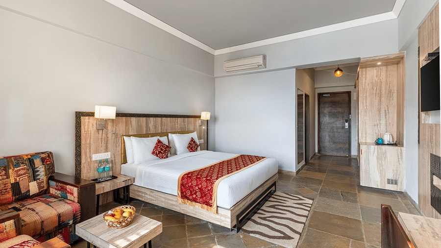 A bedroom with with a made bed and pilows on it, beside it is a table and a chair neatly arranged - Via Lakhela Resort & Spa