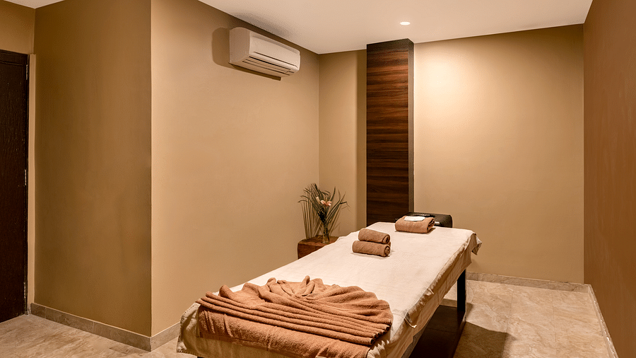 A massage room with a table, towels, and a small flower arrangement - Via Lakhela Resort & Spa, Kumbhalgarh