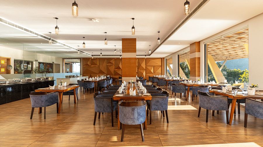 Restaurant interior with tables, chairs, and large windows under a warm lighting - 