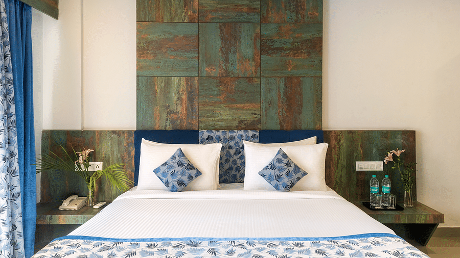 A bedroom with a made bed, decorative pillows, and artwork on the wall - Via Lakhela Resort & Spa