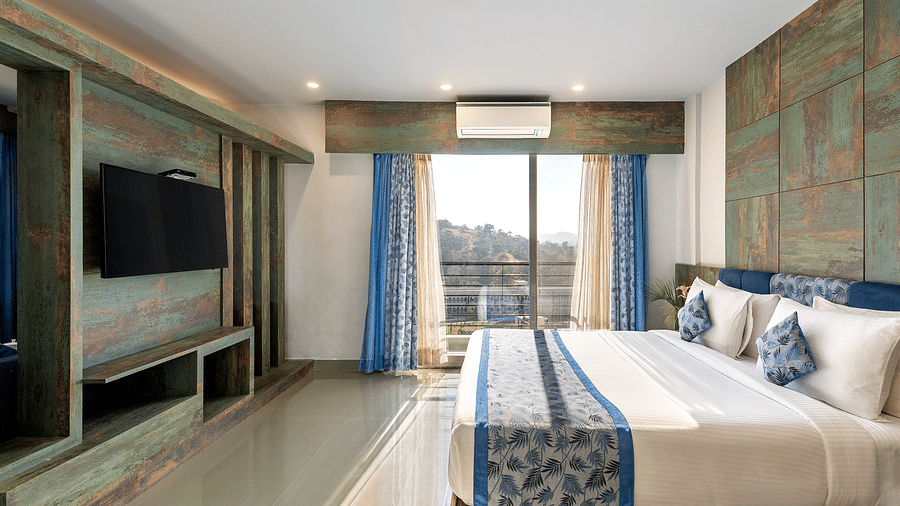A bedroom with a neatly arranged bed and a tv mounted on the wall - Via Lakhela Resort & Spa